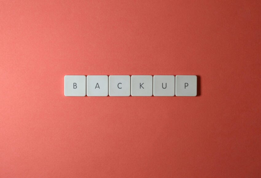 Free Close-up of keyboard keys spelling 'BACKUP' placed on a coral-colored surface. Stock Photo