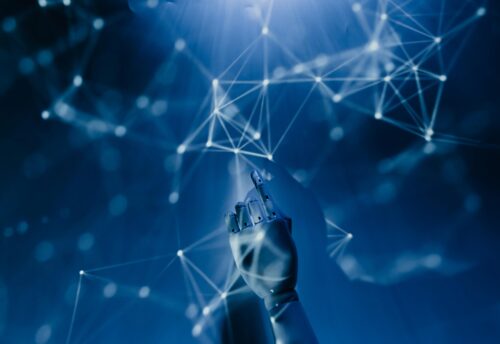 Free A robotic hand reaching into a digital network on a blue background, symbolizing AI technology. Stock Photo